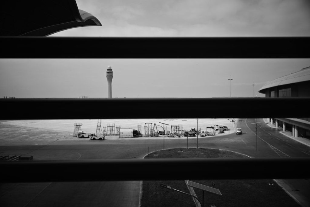 Svart-hvitt bilde av en flyplass under konstruksjon sett gjennom rister.