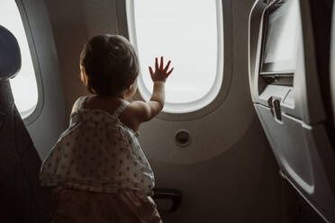Lite barn ser ut av flyvinduet under en flyreise